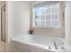 A white bathtub is set beneath a bright window for pleasant bathing at 5803 Lindley Crescent Dr, Indian Trail, NC 28079