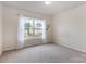 Neutral bedroom showcasing a large window with white curtains, carpeted floor, and ample natural light at 5803 Lindley Crescent Dr, Indian Trail, NC 28079