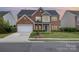 Charming two-story red brick home with attached garage and well-manicured front lawn at 5803 Lindley Crescent Dr, Indian Trail, NC 28079