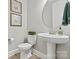 A modern powder room with a stylish pedestal sink, decorative mirror, and elegant wall art at 7549 Short Putt Ct, Charlotte, NC 28215
