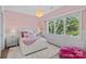 Charming pink bedroom with a plush rug, white furniture, and a sunlit window at 7861 Live Oaks Dr, Denver, NC 28037