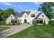 Beautiful white brick home with manicured lawn, lush landscaping, and a circular driveway at 7861 Live Oaks Dr, Denver, NC 28037