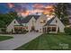 Striking white brick home with dark trim, manicured lawn, and lush landscaping at sunset at 7861 Live Oaks Dr, Denver, NC 28037