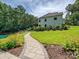 Landscaped backyard featuring a stone walkway, lush lawn, and a tranquil pond surrounded by beautiful plants at 7927 Fairmont Dr, Waxhaw, NC 28173