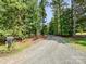 Gravel driveway leading to the property, surrounded by lush trees and natural landscape at 7927 Fairmont Dr, Waxhaw, NC 28173