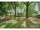 Spacious backyard with mature trees, a fire pit, a seating area, and lush green surroundings at 8936 Rittenhouse Cir, Charlotte, NC 28270