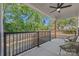 Covered patio with ceiling fan, wood beams, black metal railings, and wooded backyard views at 1 Linestowe Dr, Belmont, NC 28012