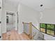 A modern staircase with wood railing and open landing, offering natural light from a large window at 1 Linestowe Dr, Belmont, NC 28012