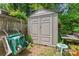 Tan Rubbermaid shed in backyard with lawnmower on the left and a small table and stool on the right at 11913 Little Stoney Ct, Charlotte, NC 28269