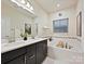 Bright bathroom featuring a soaking tub, double vanity, and window with blinds, blending functionality and style at 12641 Glowing Peak Rd, Huntersville, NC 28078