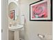 Cozy powder room features pedestal sink, round mirror, and rose artwork at 12641 Glowing Peak Rd, Huntersville, NC 28078