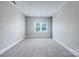 Empty bedroom featuring soft carpet, neutral walls, and a bright window, ready for personalization and comfort at 151 Harper Lee St, Davidson, NC 28036