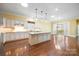 Open-concept kitchen featuring white cabinets, granite countertops, an island, and hardwood floors, flowing into the adjacent room at 16919 Hedgerow Park Rd, Charlotte, NC 28277