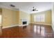 Cozy living room featuring hardwood floors, a fireplace with a white mantle, a ceiling fan, and natural light from the window at 16919 Hedgerow Park Rd, Charlotte, NC 28277