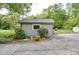 View of detached garage with neutral siding, updated window, mature landscaping, and cracked driveway at 20337 Nc Hwy 73 Hwy, Albemarle, NC 28001