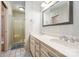 Bathroom showcasing a double vanity with a large mirror, striped walls, and a walk-in shower with glass door at 2643 Rolling Hills Dr, Monroe, NC 28110