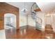 Spacious living room with hardwood floors, spiral staircase, and brick archway at 2643 Rolling Hills Dr, Monroe, NC 28110
