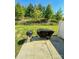 This concrete back patio shows outdoor space with a covered and open grill and green trees and grass surrounding at 2752 Sawbridge Ln, Gastonia, NC 28056