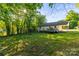 Wide shot of the large backyard that offers green grass, mature trees, and ample sunlight at 304 W Fourth St, Cherryville, NC 28021