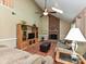 Living room with vaulted ceiling, brick fireplace, and a wooden entertainment center at 3612 Woodnotch Ct, Charlotte, NC 28269