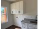 Well-lit laundry room with granite countertops, white cabinetry and dark hardware at 4034 Daugherty Rd, China Grove, NC 28023