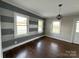Sunlit bedroom with hardwood floors, striped accent wall, and modern light fixture, offering a cozy atmosphere at 406 S Catawba St, Lancaster, SC 29720