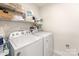 A functional laundry room with a white washer and dryer and shelving for organized storage at 4219 Mackinnon Dr, Charlotte, NC 28214