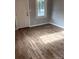 Bright living room featuring hardwood floors, gray walls, a window with natural light and a white door at 424 Skyland Ave, Charlotte, NC 28205
