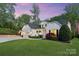 Side view of a beautifully landscaped home with a well-maintained lawn and three-car garage at 5490 Sapwood Ct, Denver, NC 28037