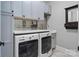 Laundry room featuring modern washer and dryer units, ample cabinet space, and a tiled backsplash at 5490 Sapwood Ct, Denver, NC 28037