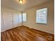 Bedroom featuring hardwood floors, a closet, and two windows providing natural light at 5812 Hunting Ridge Ln # A, Charlotte, NC 28212