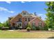 Charming two-story brick home featuring manicured landscaping, mature trees, and a welcoming entryway under a blue sky at 733 Lingfield Ln, Waxhaw, NC 28173