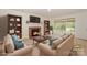 Staged living room with a fireplace, built-in bookshelves, sofas, and large windows overlooking a fenced yard at 8709 Stratton Farm Rd, Huntersville, NC 28078