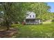 Lush front lawn view of this home, featuring a screened front porch, mature trees and blooming plants at 105 Horsestable Ct, Mooresville, NC 28115