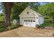 Detached garage featuring a star decoration, with a gardening area and lush trees surrounding the structure at 105 Horsestable Ct, Mooresville, NC 28115