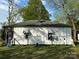 A white, single-story home with a dark roof and black door, showing its side profile with window awnings at 1210 Congress St, Gastonia, NC 28054