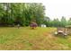 Large backyard with green grass, mature trees, wooden swing, and shed in the background at 1215 Eastcreek Rd, Fort Lawn, SC 29714