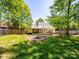 This backyard features a screened-in porch, a patio, and a fire pit surrounded by green grass at 1257 Mill Race Ln, Matthews, NC 28104