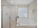 Bathroom featuring a bathtub and separate glass enclosed shower, and natural light from a large window at 1257 Mill Race Ln, Matthews, NC 28104