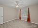 Neutral bedroom with light wood flooring, ceiling fan, and bright window with orange curtains at 1257 Mill Race Ln, Matthews, NC 28104