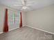 Neutral bedroom with light wood flooring, ceiling fan, and a bright window with orange curtains at 1257 Mill Race Ln, Matthews, NC 28104
