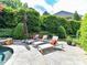 Backyard patio features lounge chairs, lush greenery and privacy hedge, and a stone tile surface at 14650 Trading Path Way, Charlotte, NC 28277