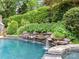 Custom backyard features a luxurious pool with tranquil waterfall feature and lush landscaping at 14650 Trading Path Way, Charlotte, NC 28277