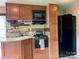 RV kitchen featuring wood cabinetry, black appliances, laminate countertops, and tile flooring at 148 Sunshine Trl # A165, Mount Gilead, NC 27306