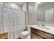 Well-lit bathroom with a wooden vanity, a sink, a toilet, and a bathtub with a floral curtain at 14925 Baldridge Dr, Huntersville, NC 28078