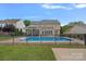 Spacious backyard featuring an in-ground pool, fenced yard, a covered patio, and lush greenery for outdoor enjoyment at 156 Pecan Hills Dr, Mooresville, NC 28115