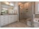 Bright bathroom features a glass enclosed shower with bench, double vanity, and light gray tile flooring at 16711 Monocacy Blvd, Huntersville, NC 28078