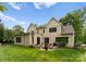 Exterior view of the two-story home showcasing a paver patio, fire pit, lush lawn, and mature trees at 20614 Pointe Regatta Dr, Cornelius, NC 28031