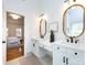 Bright bathroom featuring double sinks, a vanity area, updated lighting and mirrors, and access to the primary bedroom at 216 Liriope Ct, Matthews, NC 28105