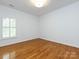 Minimalist bedroom boasts hardwood floors, bright natural light from the shuttered window and white walls at 216 Liriope Ct, Matthews, NC 28105